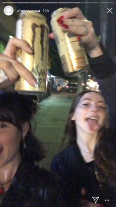 two women are smiling and holding up cans with food on them while another woman is taking a selfie