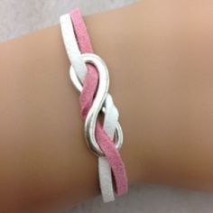 a close up of a person's arm wearing a pink and white leather bracelet