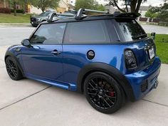 a small blue car parked on the side of a road with its roof rack open