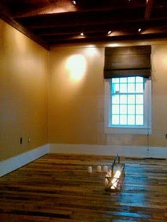 an empty room with wooden floors and lights on the windows sill, in front of a window