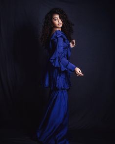 a woman in a blue dress posing for the camera with her hand on her hip