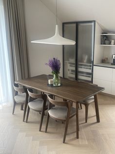 a dining room table with chairs and a vase filled with flowers on top of it