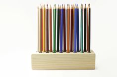 a group of colored pencils sitting on top of a wooden holder with different colors