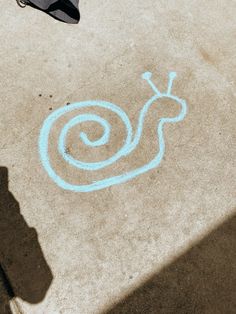 the shadow of a person standing next to a sidewalk with a snail drawn on it