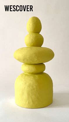 a stack of yellow rocks sitting on top of a white floor next to a wall