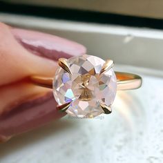 a woman's hand holding an engagement ring with a large diamond in the center