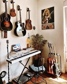 a room with guitars and musical equipment on the wall, including an electric keyboard in front of a window