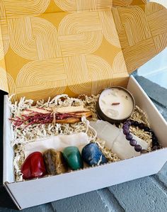 an open box filled with different types of rocks and candles on top of a table