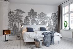 a bedroom with white walls and trees painted on the wall