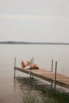 two people laying on a dock in the water