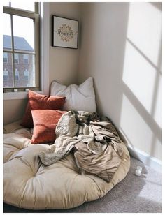 an unmade bed in the corner of a room with pillows and blankets on it