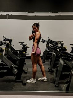 a woman taking a selfie in front of a gym machine with her cell phone