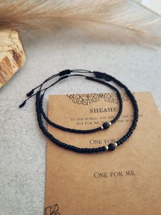 two bracelets sitting on top of a piece of paper next to a feather pen