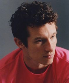 a man with curly hair wearing a red shirt