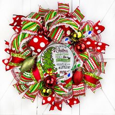 a red and green christmas wreath hanging on a white wooden door with polka dot ribbon