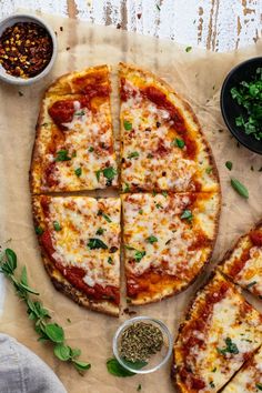 several slices of pizza sitting on top of a table next to bowls and sauces