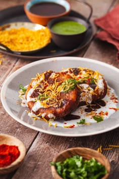 a white plate topped with food next to bowls of sauces and condiments