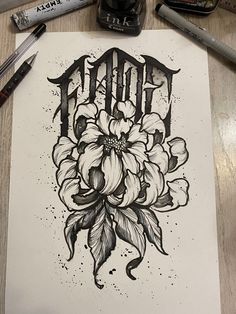 an ink drawing of flowers and the word tattoo on paper next to some marker pens