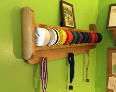 a wooden rack with ribbons and medals hanging on it's side against a green wall