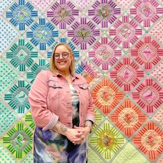 a woman standing in front of a colorful quilt