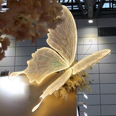 a large white butterfly sitting on top of a metal object in a room with tiled walls