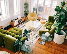 a living room filled with lots of green furniture and large potted plants in the corner