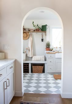 an archway leading into a kitchen with white cabinets and checkered flooring on the walls