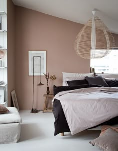 a bed sitting in a bedroom next to a window with a lamp on top of it