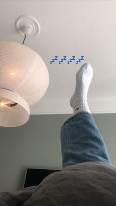 someone is laying down on the bed with their feet up in the air and there are two lights above them