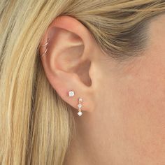 a close up of a woman's ear with two small diamond earrings on it