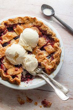 two scoops of ice cream are on top of a berry pie with spoons