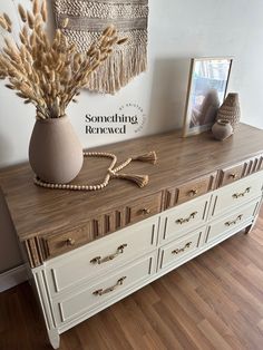 a white dresser with some dried plants on top