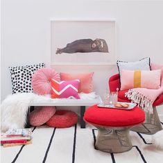 a living room filled with lots of colorful pillows and furniture on top of a striped rug