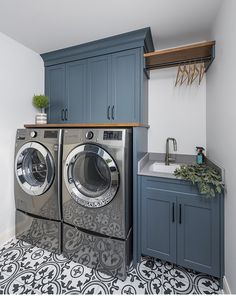 a washer and dryer in a laundry room with blue cabinetry on the wall