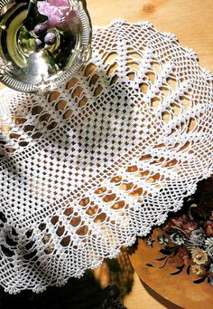 an image of a doily on a table with flowers in a glass vase and other items