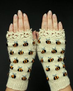 two hands wearing knit mittens with bees on them