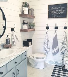 a white bathroom with black and white towels hanging on the rack next to the toilet