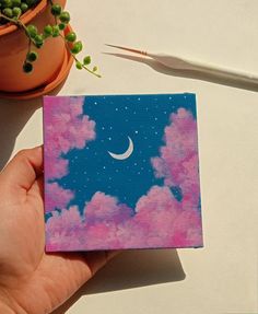 a hand holding up a small card with the moon and stars in the sky on it