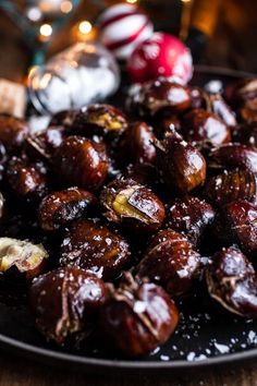 a plate full of roasted dates on a table with christmas decorations in the back ground