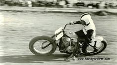 a man riding on the back of a motorcycle down a dirt road