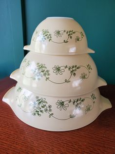 three white dishes stacked on top of each other with flowers painted on the bottom and sides