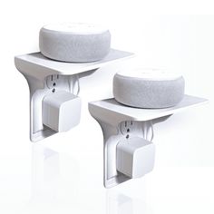 two white speakers sitting on top of each other in the shape of wall hooks and brackets