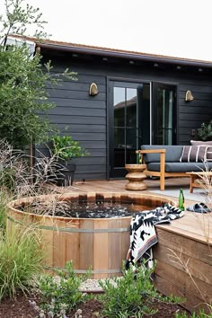 a backyard with a hot tub and patio furniture in the foreground, next to a wooden deck