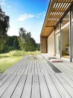 a wooden deck with two chairs on it next to a sliding glass door and trees