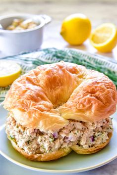 a chicken salad sandwich on a plate with lemons in the background