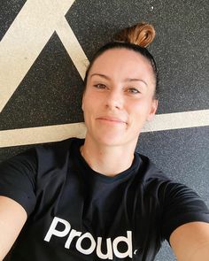 a woman laying on the ground with her hair in a top knot and proud t - shirt