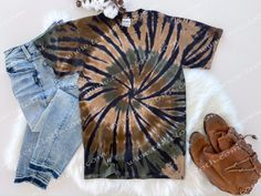 a tie - dyed shirt, jeans and shoes are laid out on a fur rug