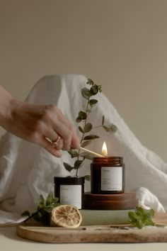 a person lighting a candle on top of a cutting board next to a lemon slice