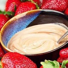 a bowl filled with peanut butter surrounded by strawberries