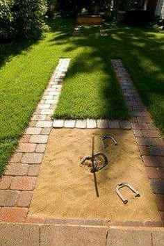 a yard with grass and tools laying on the ground in front of it, next to a brick walkway